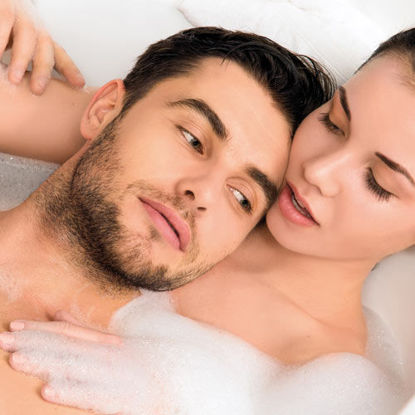 Ein Paar entspannt gemeinsam in einer mit Schaum gefüllten Badewanne und genießt die Nähe zueinander.