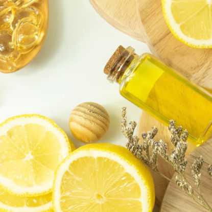 Arrangement aus Naturkosmetik-Zutaten: eine aufgeschnittene Zitrone, Massagekugeln aus Holz, ein Glas mit gelbem Öl, getrocknete Lavendelzweige und weitere Naturprodukte auf runden Holzunterlagen.