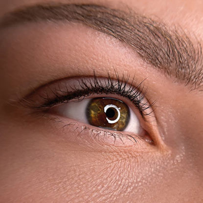 Nahaufnahme eines braunen Auges mit detaillierter Darstellung der Iris, Wimpern und Augenbraue. In der Pupille spiegelt sich ein ringförmiges Licht.