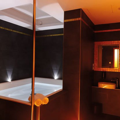 Modern gestaltender Floatingraum in SaarowTherme mit großer Floating-Wanne, beleuchtetem Spiegel über einem Waschbecken und einem aufgehängten Bademantel. Stimmungsvolle Lichtakzente schaffen eine entspannte Atmosphäre.